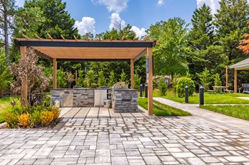 a patio with a stone grill and a wooden structure